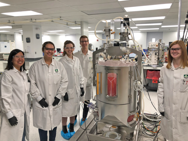 Athersys researchers standing next to bioreactor in the lab