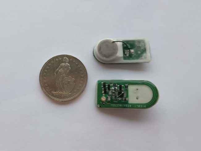 Photograph of two bioelectronic implants with a coin (diameter 27.4 mm) for comparison