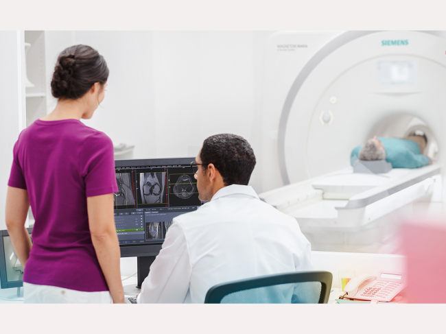 Doctor, technician look at computer while man undergoes MRI