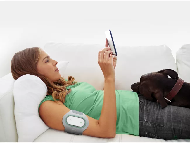 Woman lays on couch while wearing Nerivio on arm