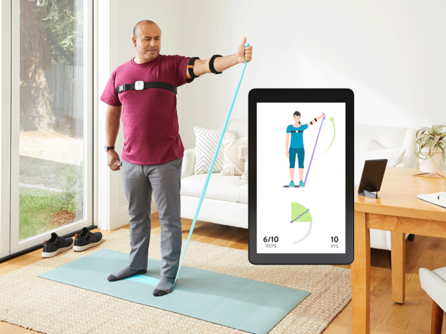 Hinge Health participant at home using wearable shoulder sensors, mobile app