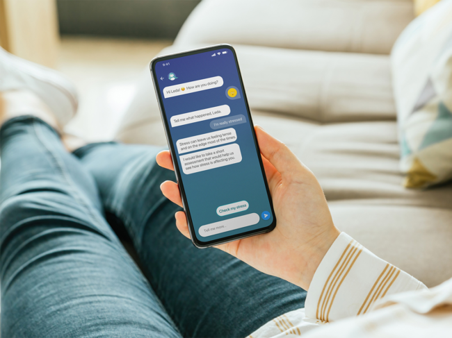 Person on couch holding smartphone displaying Wysa mental health app  