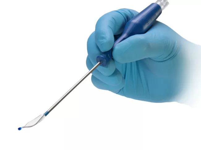 Gloved hand holding Nuvent device