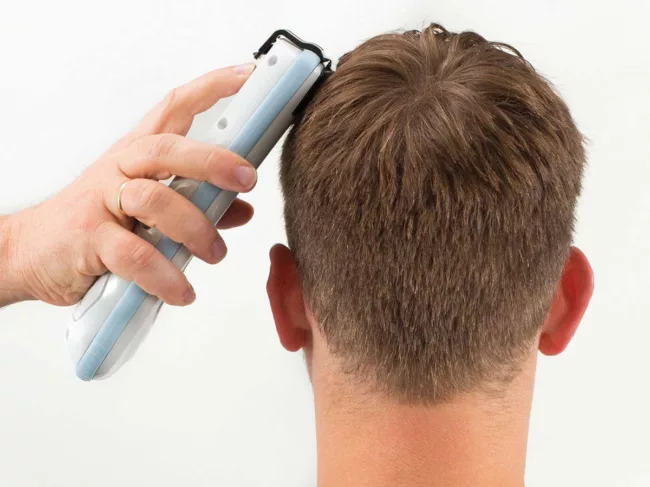 Hand places Infrascanner device on patient's head