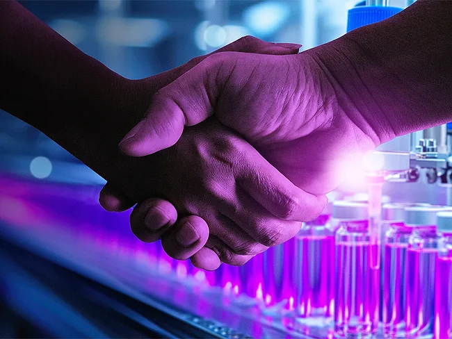 Photo of two people shaking hands near lab equipment