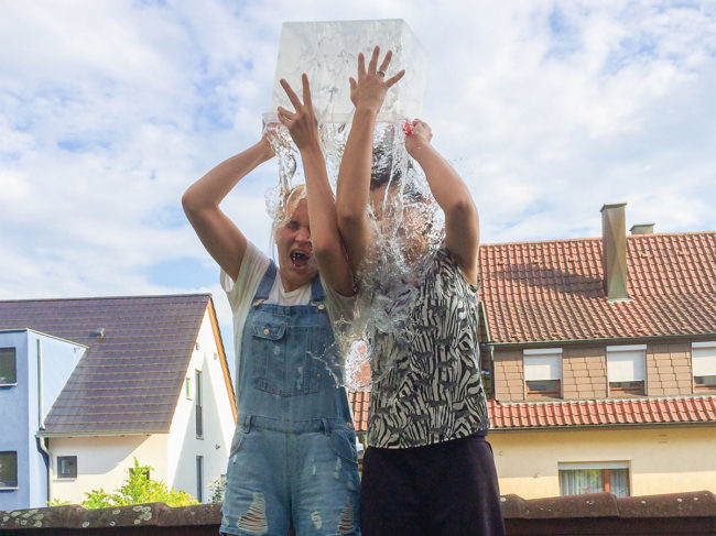 Two girls dump a bucket of water on their heads