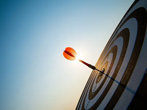 Red dart and target against blue sky