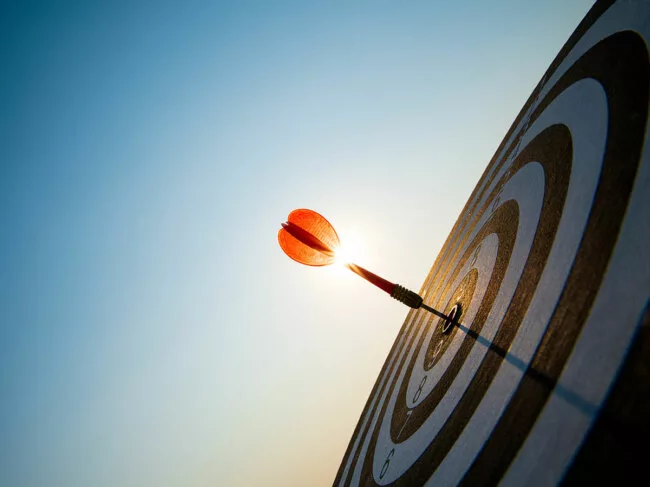Red dart and target against blue sky