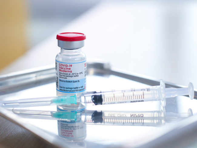 Moderna vaccine vial and syringe on tray