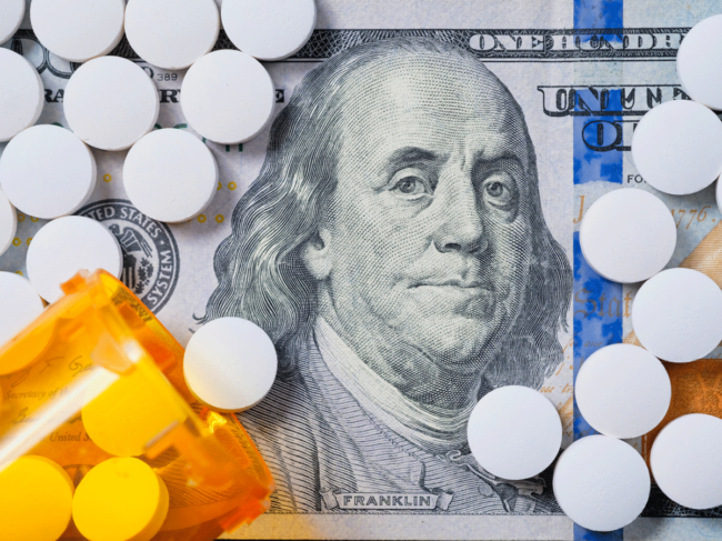 Pills, bottle atop $100 bill