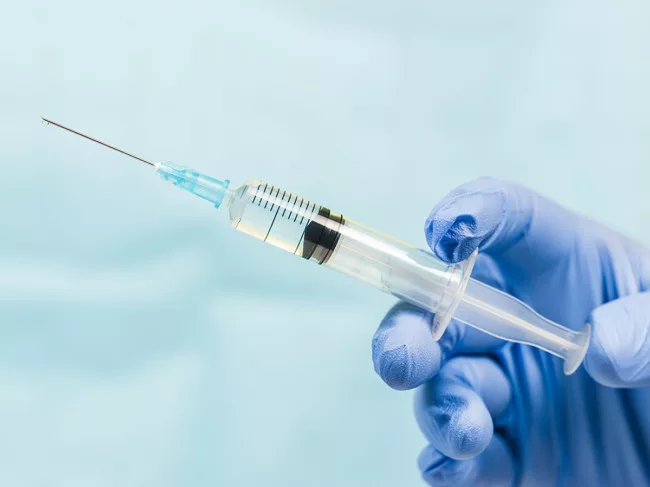 Blue gloved hand holding a syringe