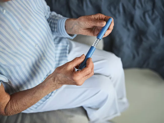 Elderly woman holding autoinjector