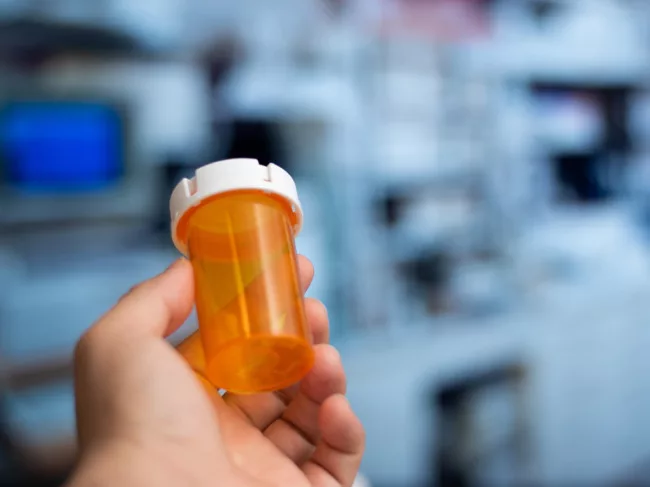 Hand holding empty medicine bottle