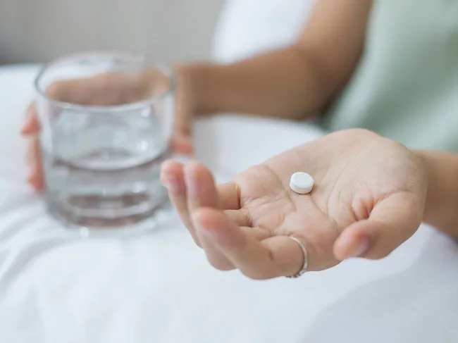 Hands holding tablet and glass of water