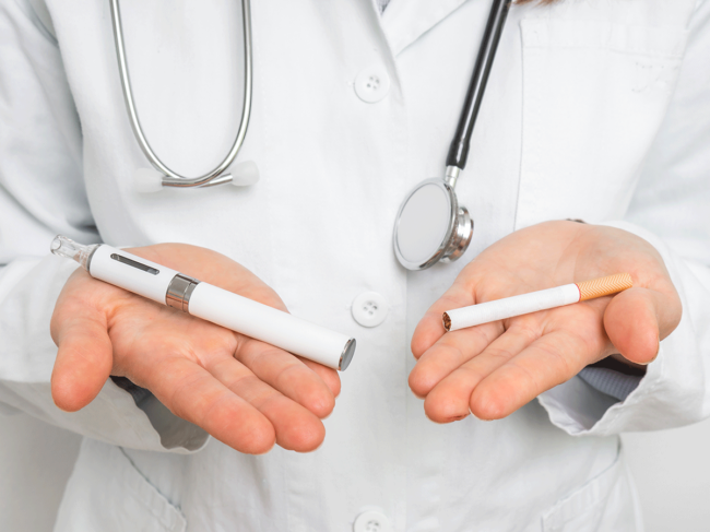 Doctor holding an e-cigarette in one hand, tobacco cigarette in the other