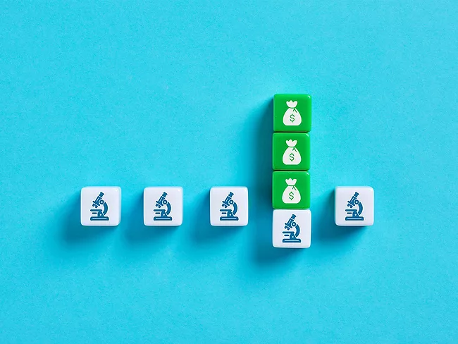 Green money bag tiles stacked on tile with microscope icon