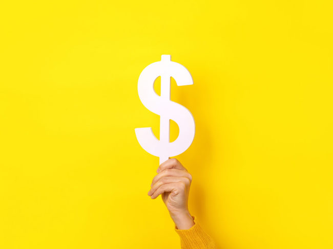 Hand holding dollar sign on yellow background