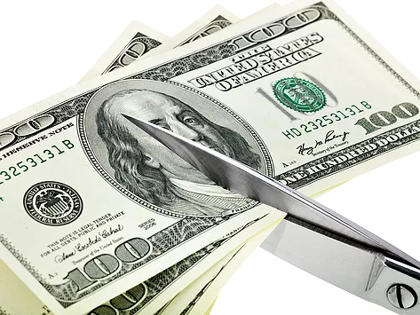 Scissors cutting stack of 100 bills