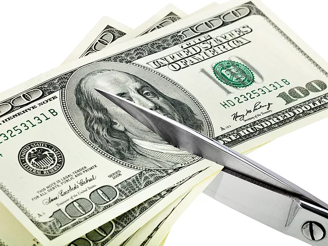 Scissors cutting stack of $100 bills