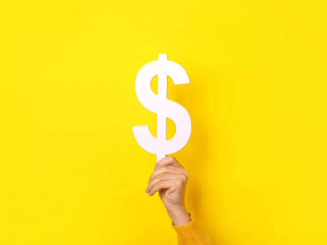 Hand holding dollar sign on yellow background