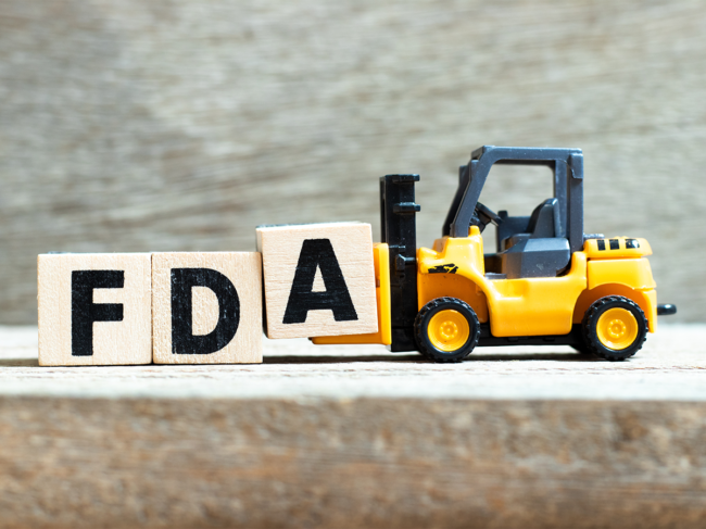 Toy bulldozer moving FDA letter blocks