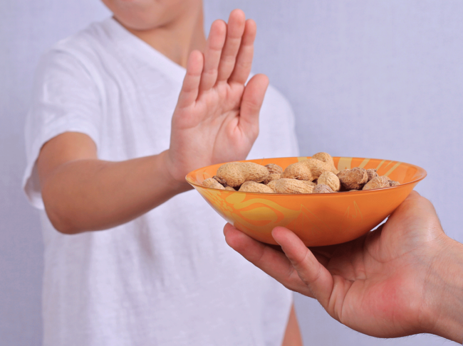 Child pushing away bowl of peanuts