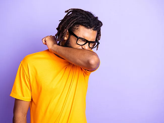 Man sneezing into elbow