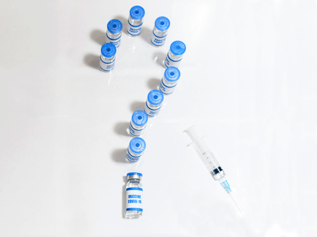 Syringe and COVID-19 vaccine vials as question mark