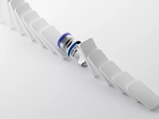 COVID-19 vial in a line of toppled dominoes
