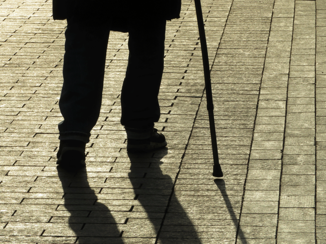 Silhouette of person walking with a cane