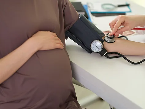 Pregnant woman with blood pressure monitor