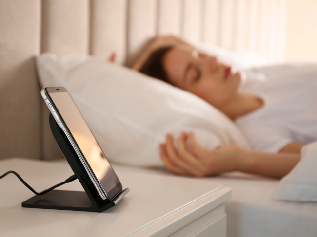 Smartphone on nightstand, woman sleeping in bed